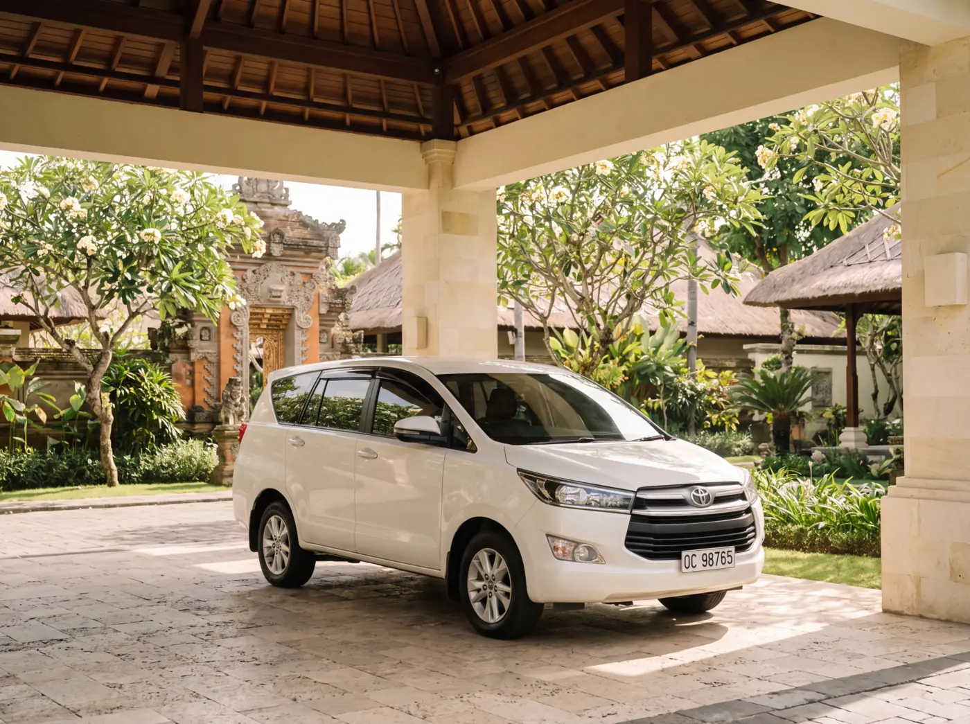 Pearl-white Toyota Innova Reborn standing at the arrival entrance of a five-star Nusa Dua beach resort